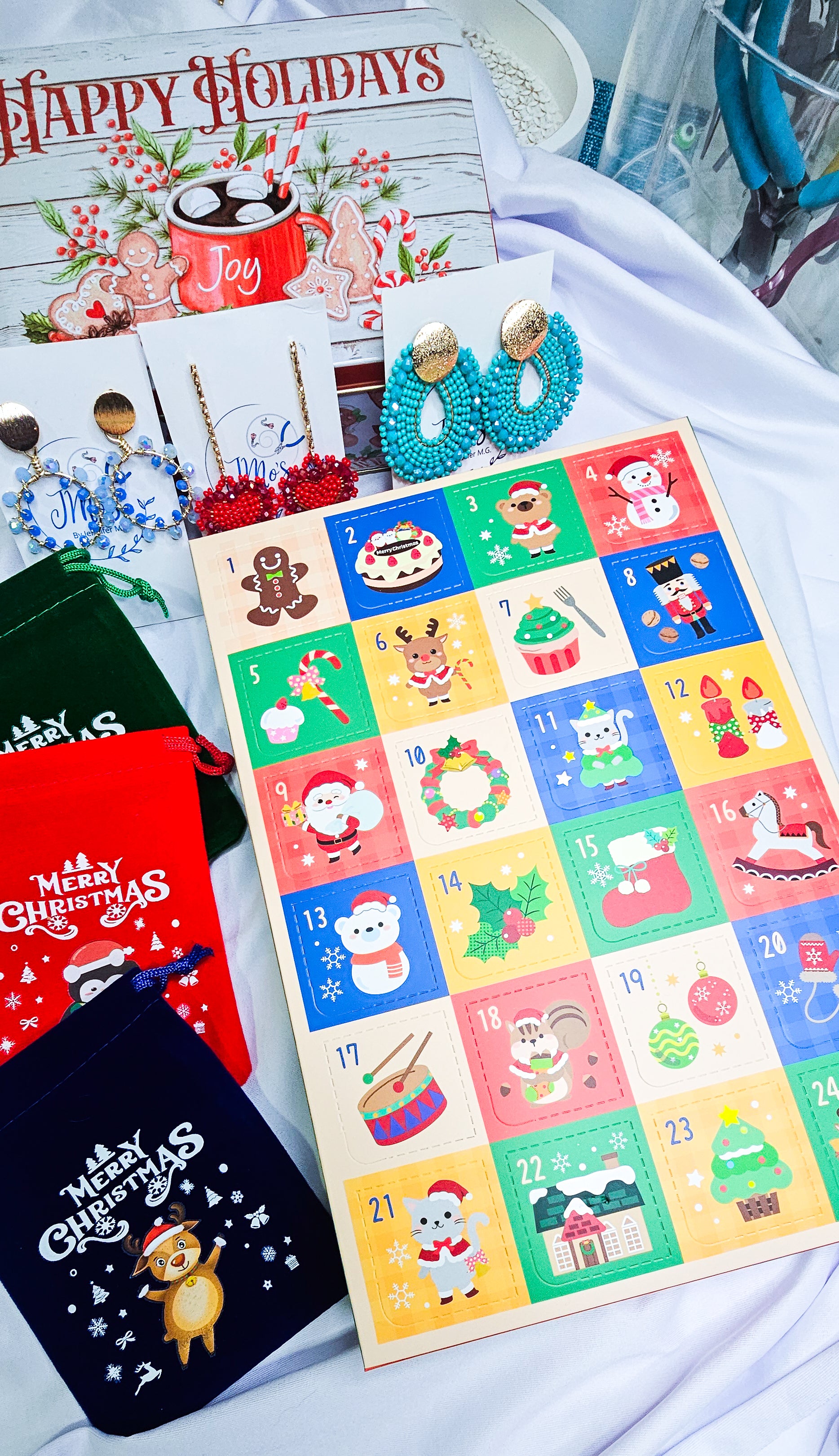 Colorful advent calendar with Christmas designs, surrounded by festive items on a white surface.
