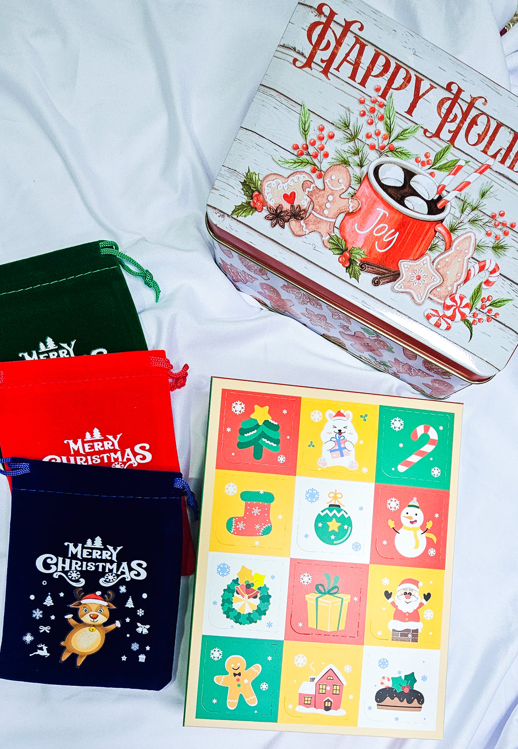 Collection of Christmas-themed items including a box with festive designs, a colorful card, and small bags.