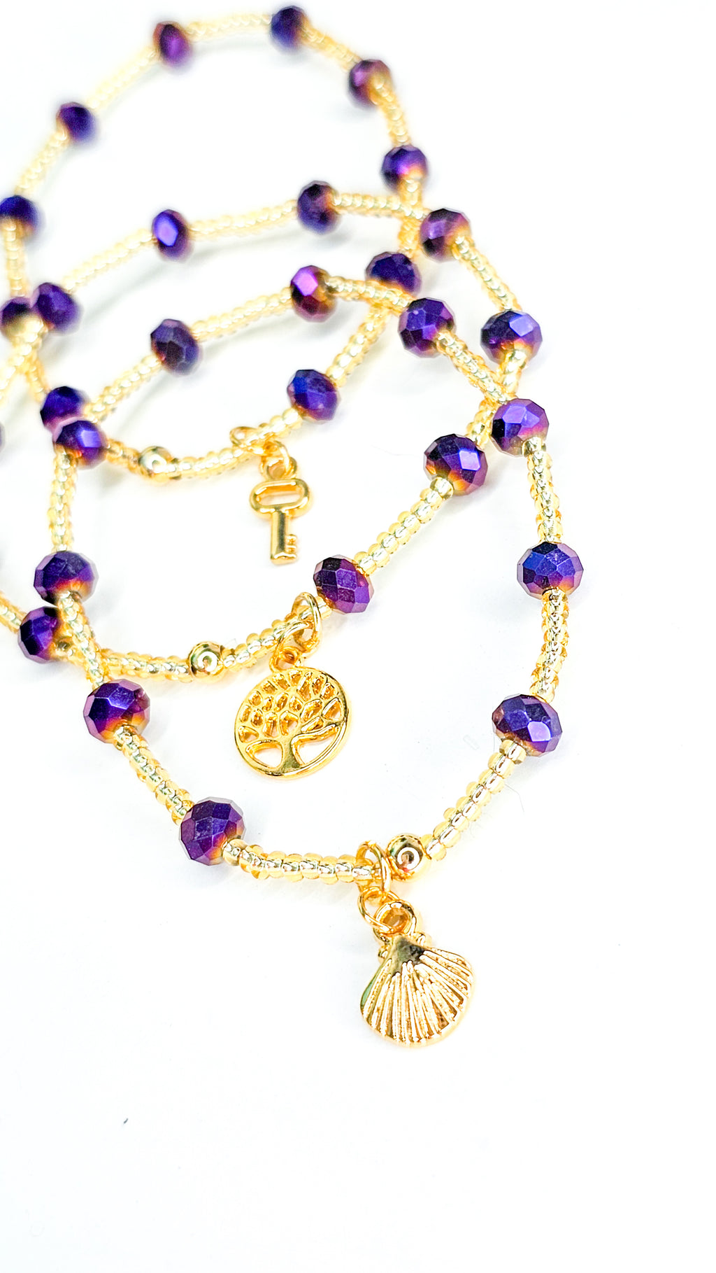 Purple beaded necklace with gold accents on a white background